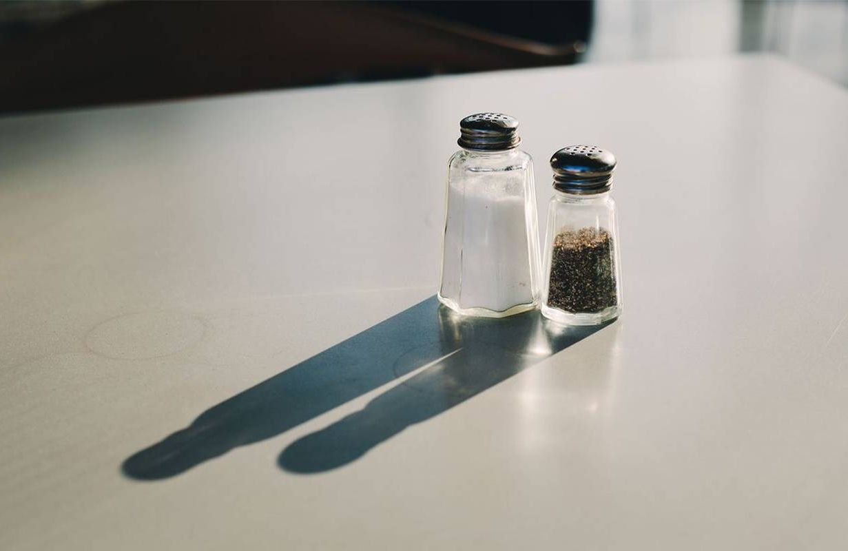 Salt and pepper shakers sitting on a table. Next Avenue, how much sodium, healthy amount of salt
