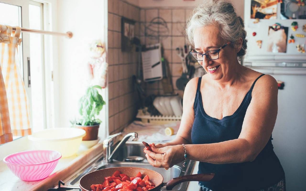 A woman cooking healthy food. Next Avenue, postmenopausal women health