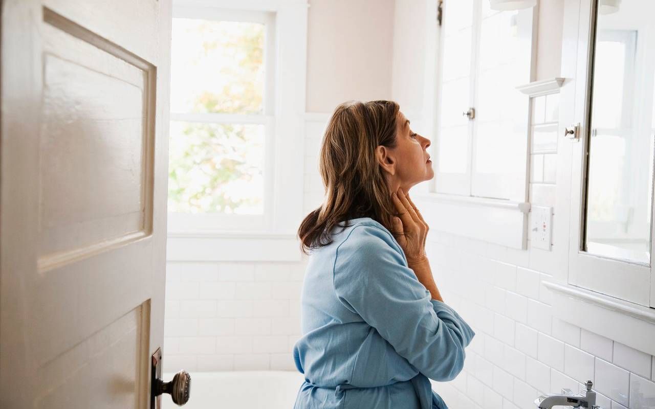 A person with rosacea looking in the mirror. Next Avenue, blushing, red cheeks