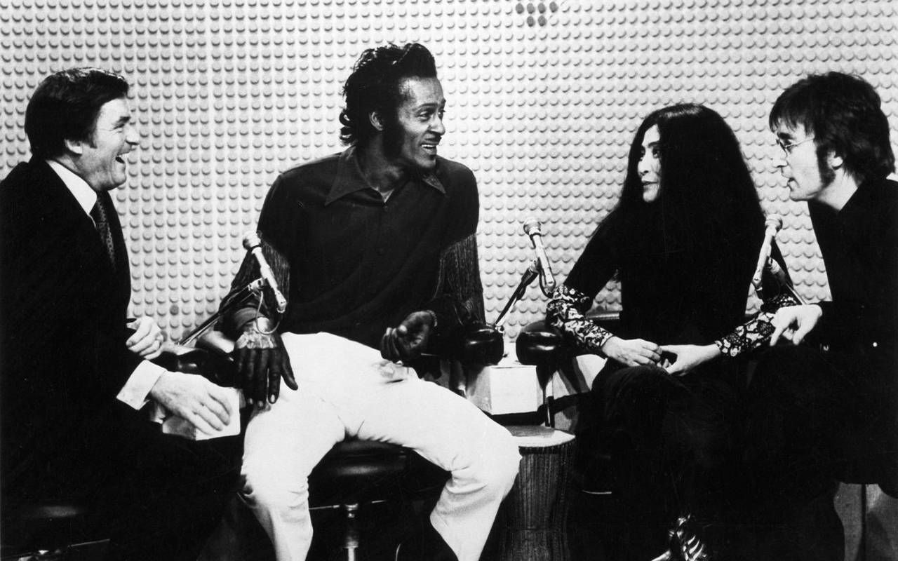 A black and white photo of four people laughing. Next Avenue, John Lennon and Yoko Ono, The Mike Douglas Show