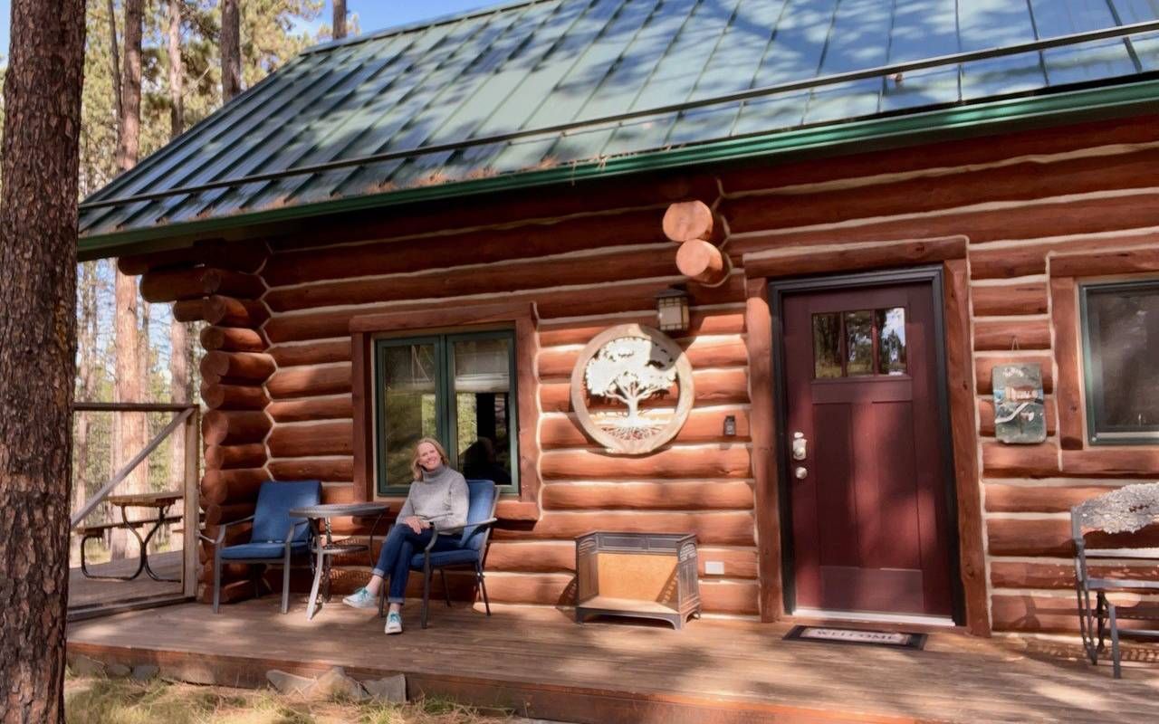 A person sitting on a cabin's front porch. Next Avenue, short term rentals