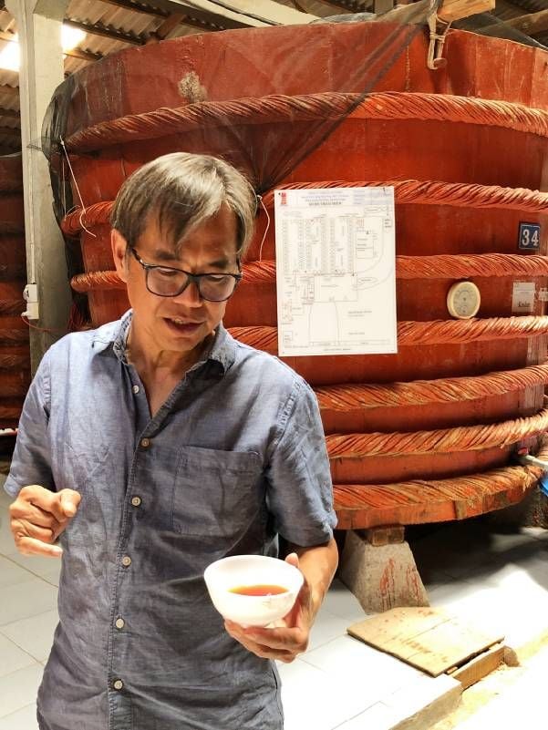 A man holding a bowl of fish sauce. Next Avenue