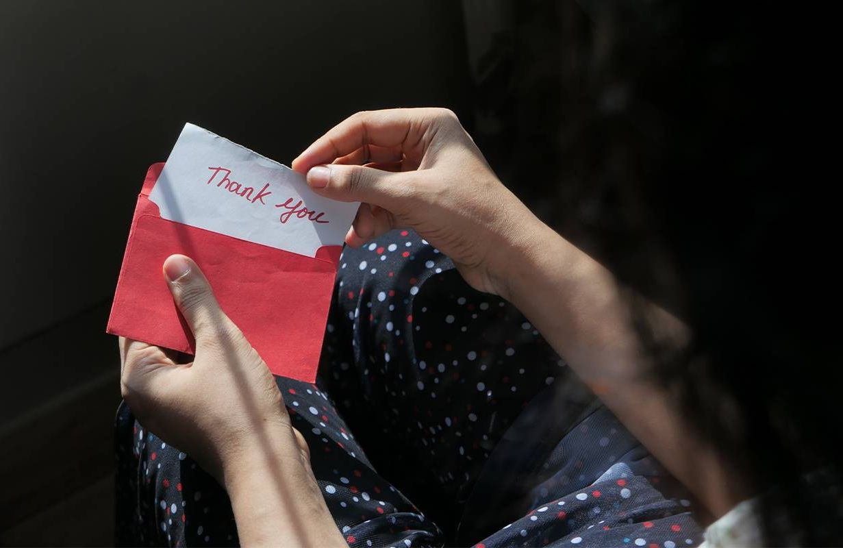 A person opening up a thank you card. Next Avenue