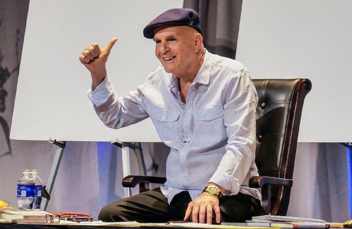 A man smiling while sitting on a stage. Next Avenue, Dr. Wayne Dyer