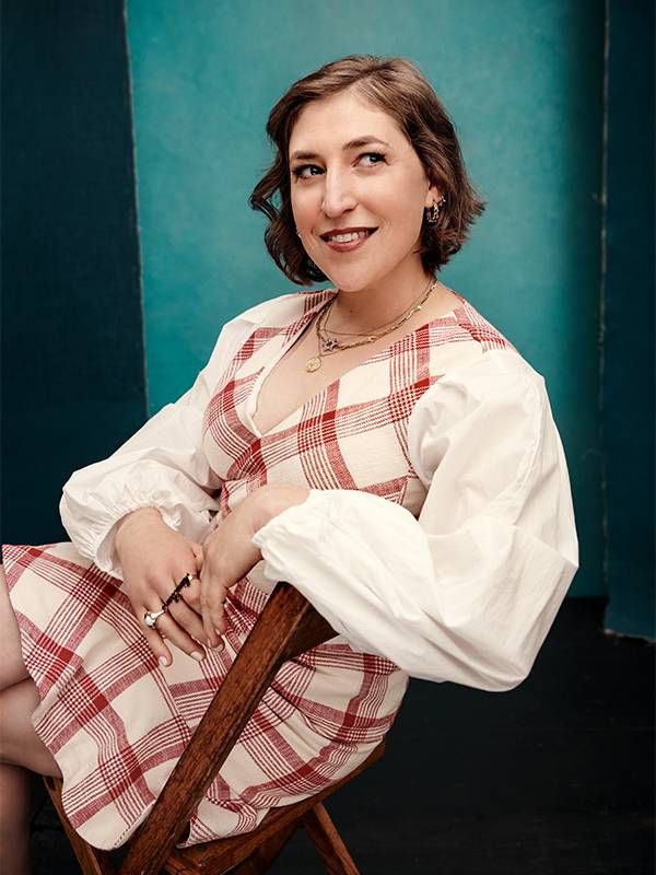 A person sitting on a stool in front of a backdrop. Next Avenue, PBS, Mayim Bialik