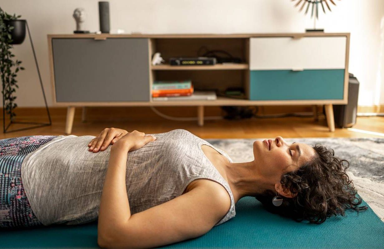 A woman doing breathing exercises at home. Next Avenue