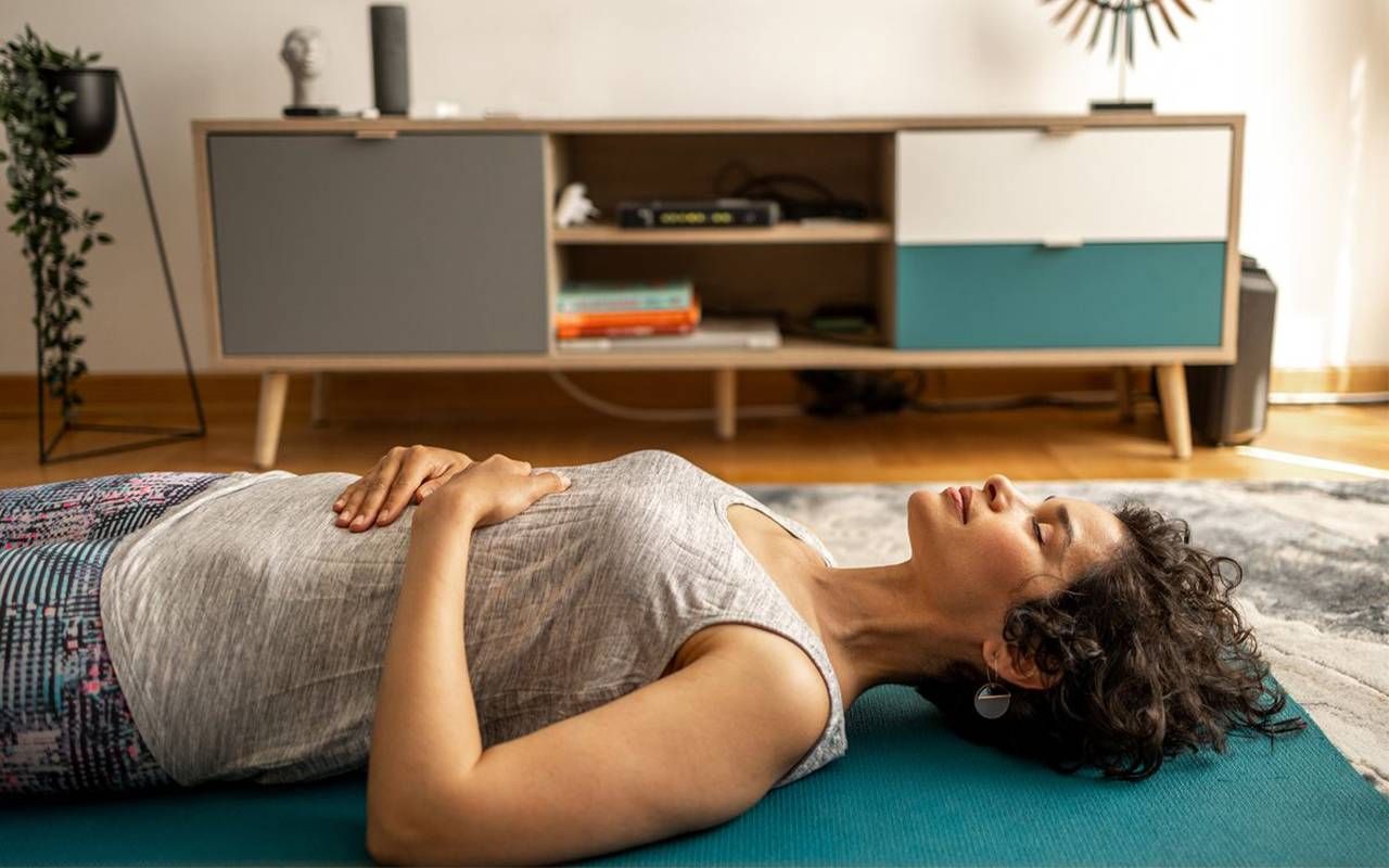 A woman doing breathing exercises at home. Next Avenue