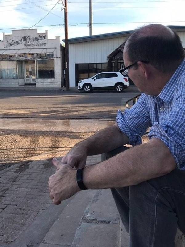 A man sitting on a street curb. Next Avenue, Century Lives Podcast