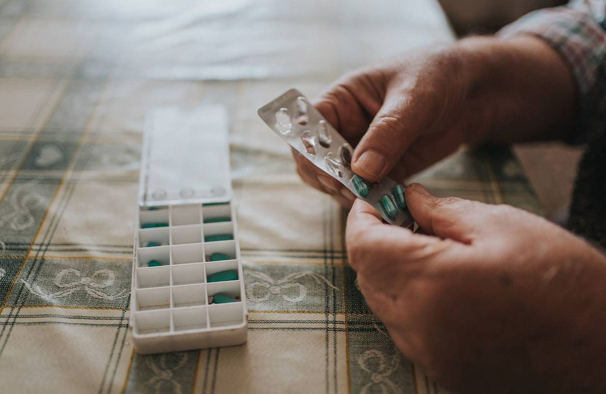 A man putting medication into a pill box. Next Avenue, HIV, older adults