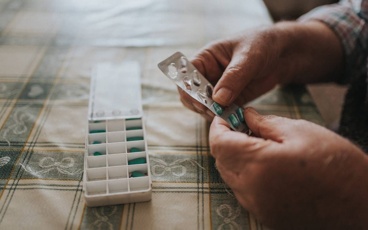 A man putting medication into a pill box. Next Avenue, HIV, older adults