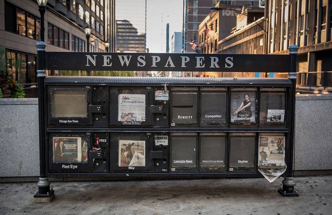 A newsstand with very few newspapers in it. Next Avenue, local news, desert