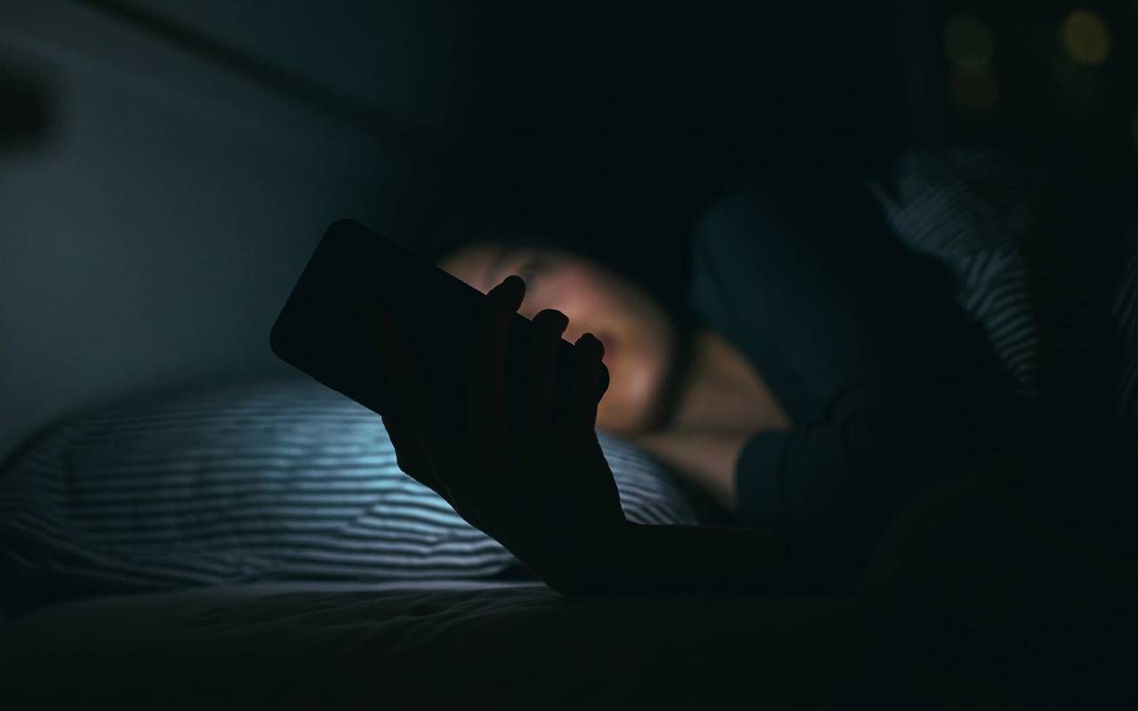 A woman answering her phone at night in bed. Next Avenue, death of sister, suicide