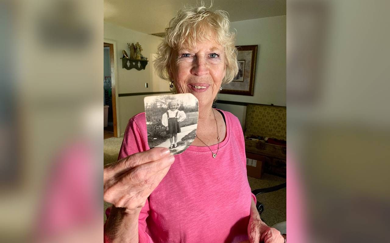 A mother holding up an older photo. Next Avenue