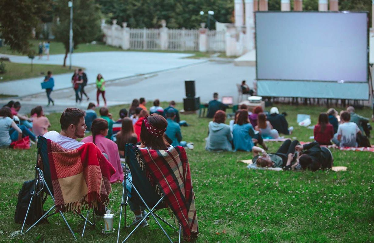 A group of people watching a movie in the park. Next Avenue, UnLonely Film Festival