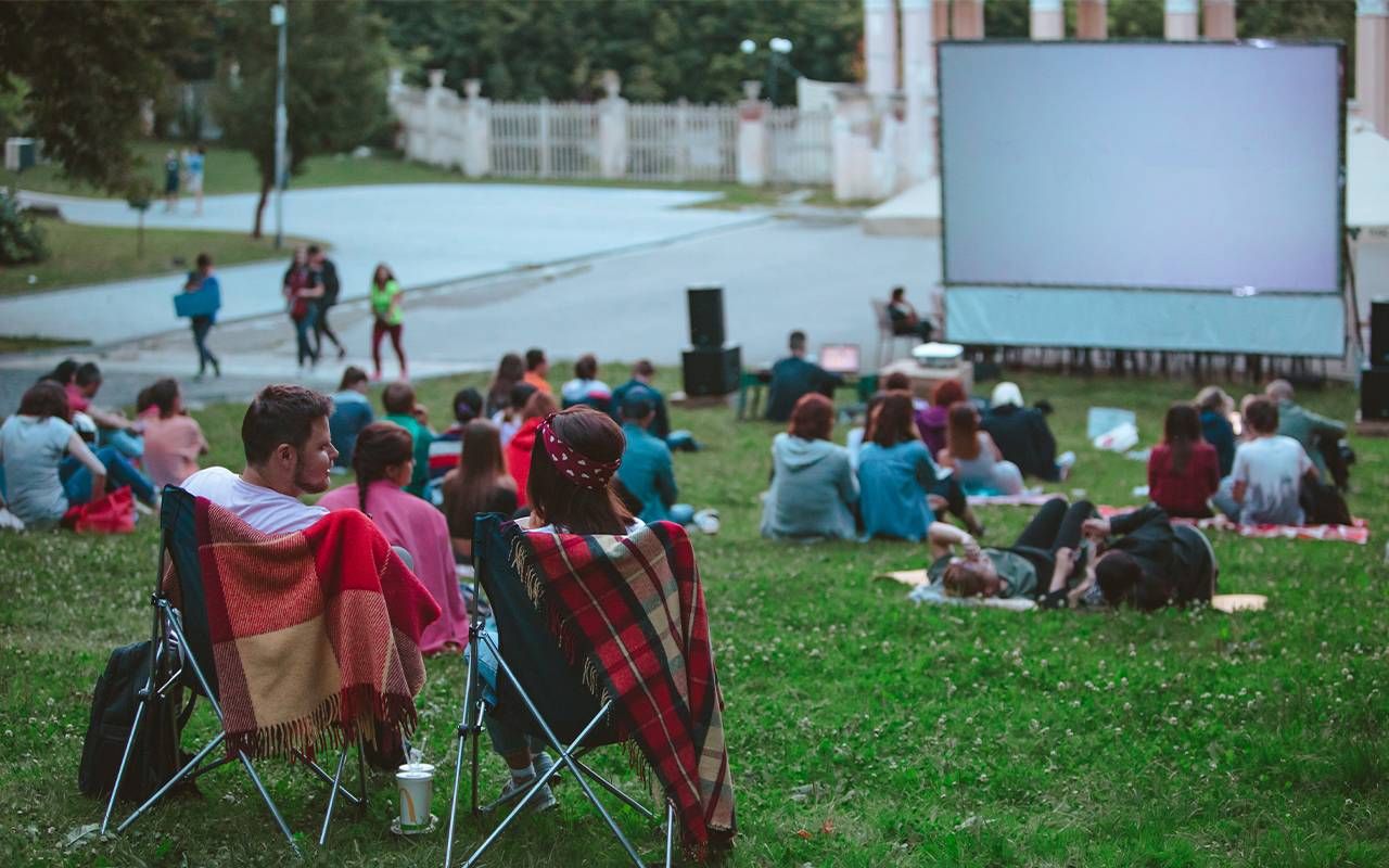 A group of people watching a movie in the park. Next Avenue, UnLonely Film Festival