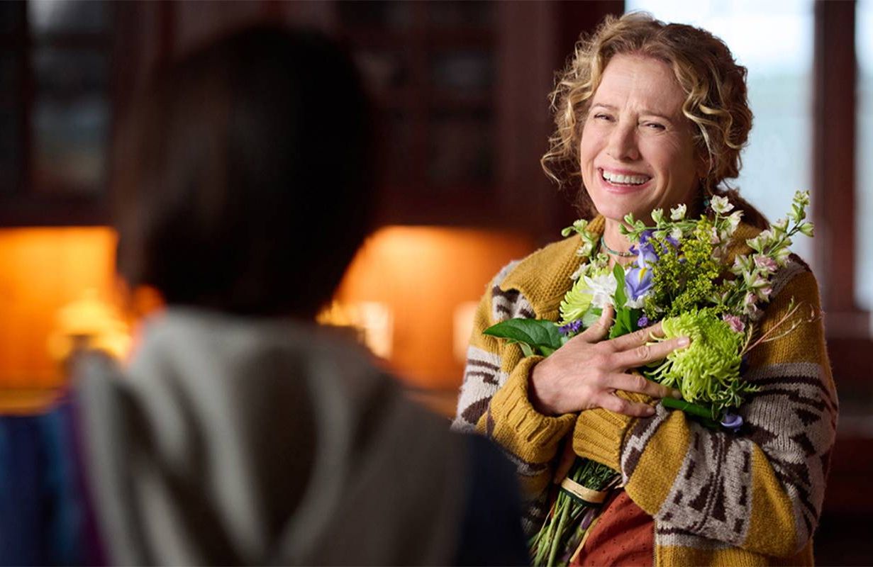 A woman holding a bouquet of flowers and smiling. Next Avenue, Nancy Travis, Hallmark, Ride
