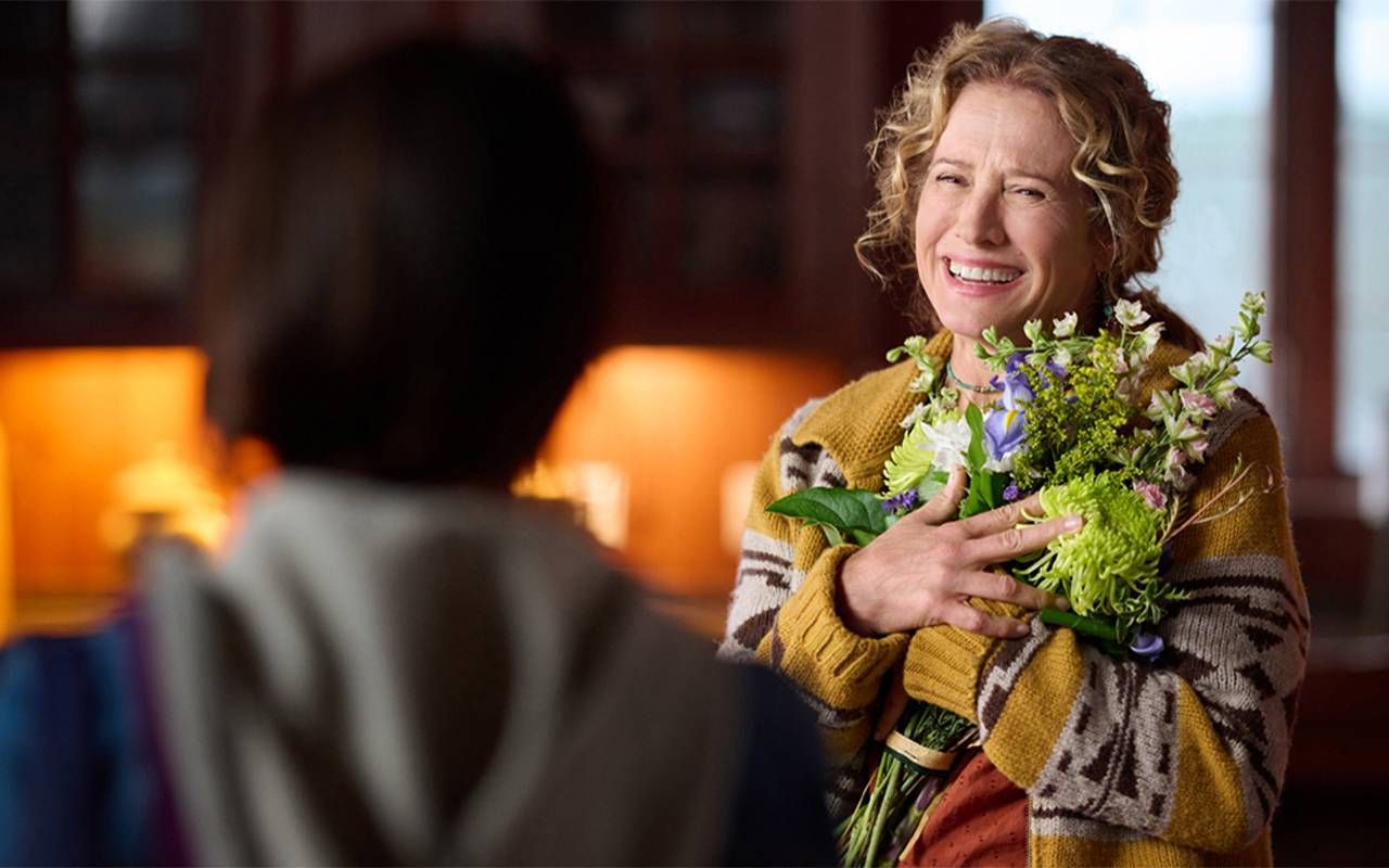 A woman holding a bouquet of flowers and smiling. Next Avenue, Nancy Travis, Hallmark, Ride
