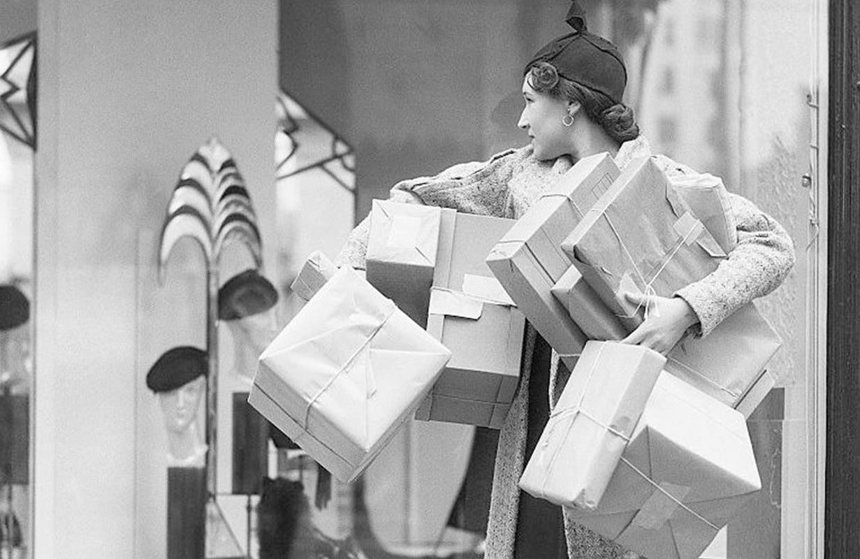 A vintage photo of a woman holding shopping boxes. Next Avenue