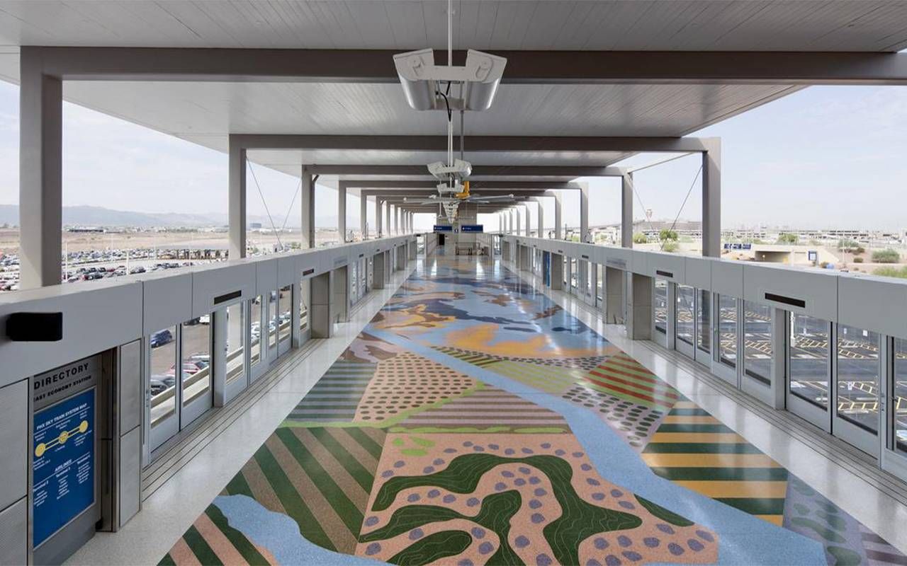 A large hallway in an airport with colorful tile flooring. Next Avenue