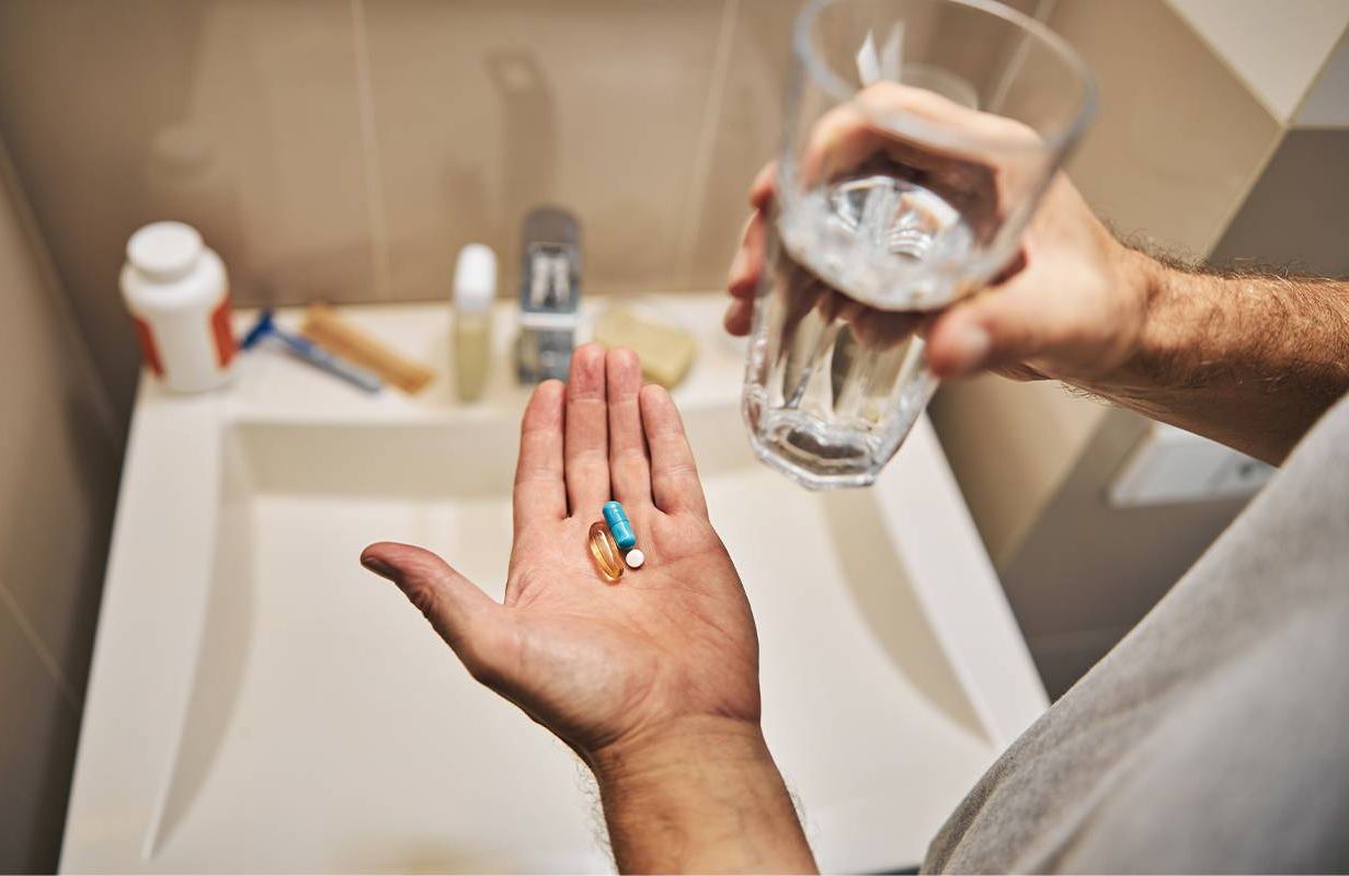 A person holding a glass of water and a vitamin D pill in their hand. Next Avenue, Vitamin D, mental health, depression