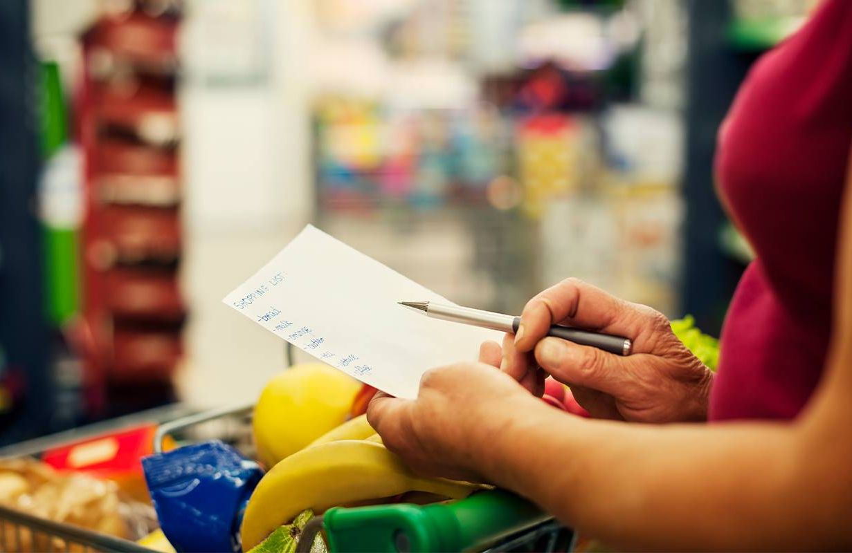 A woman looking over a shopping list at the grocery store. Next Avenue, anxiety