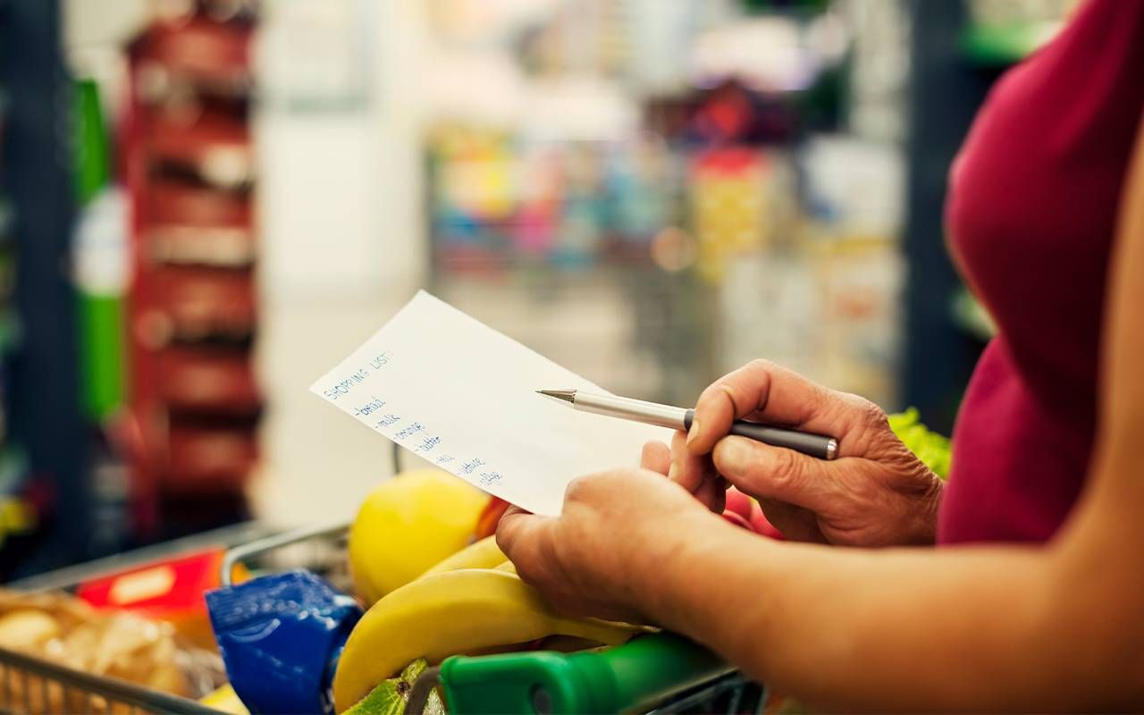 A woman looking over a shopping list at the grocery store. Next Avenue, anxiety