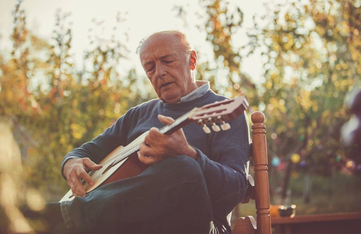 A man playing guitar in a backyard. Next Avenue