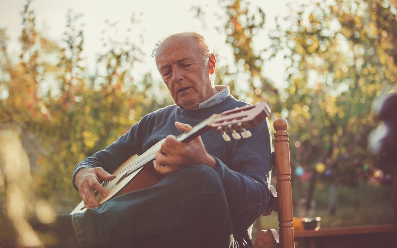 A man playing guitar in a backyard. Next Avenue