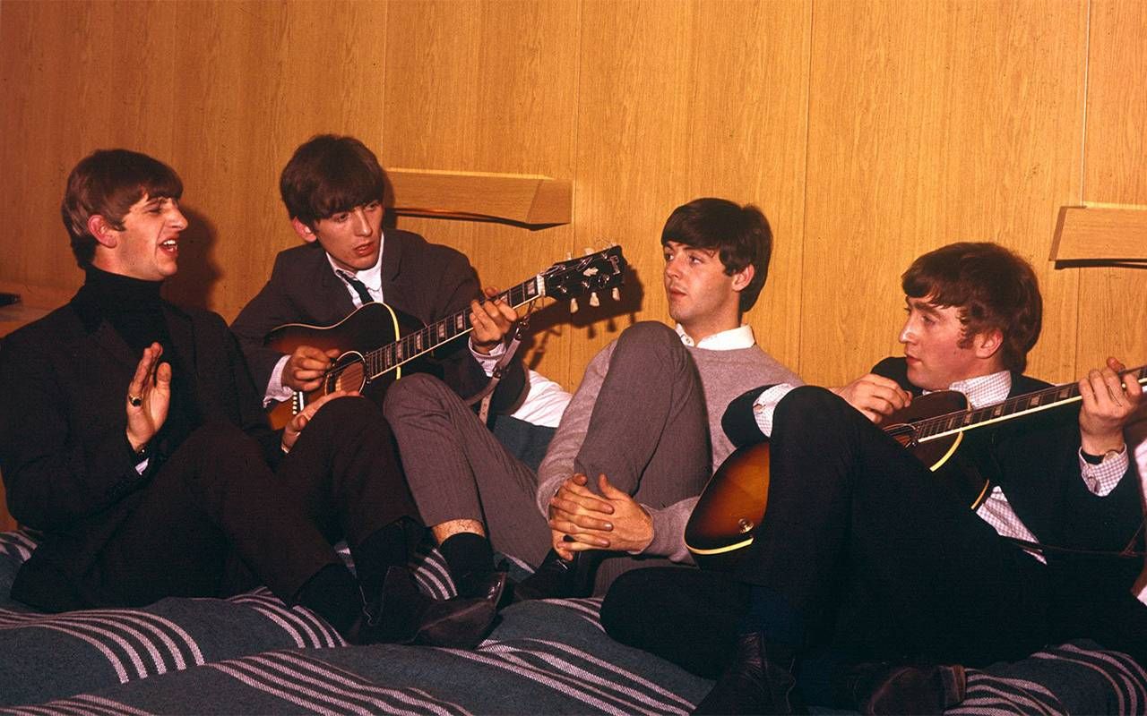The Beatles sitting on a couch together. Next Avenue
