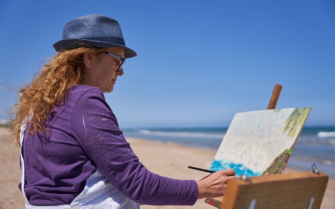 A woman painting on the beach. Next Avenue, grief