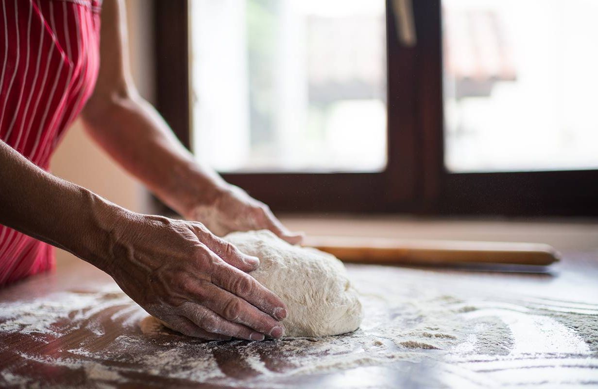 A woman kneading pizza dough. Next Avenue
