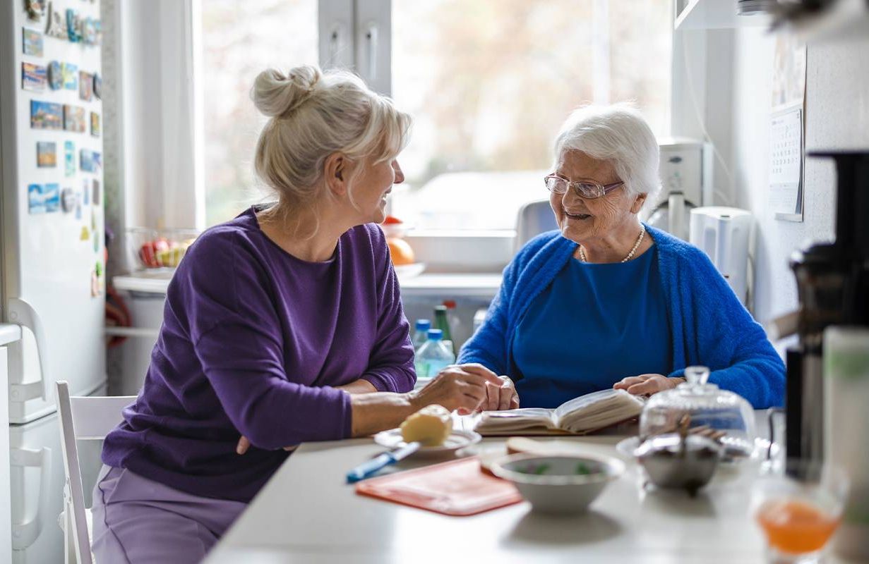 A family caregiver sitting with her mom at the kitchen table. Next Avenue