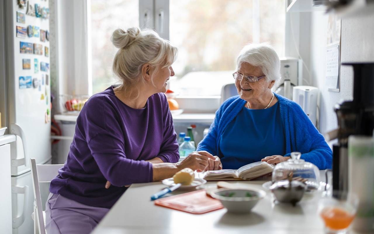 A family caregiver sitting with her mom at the kitchen table. Next Avenue