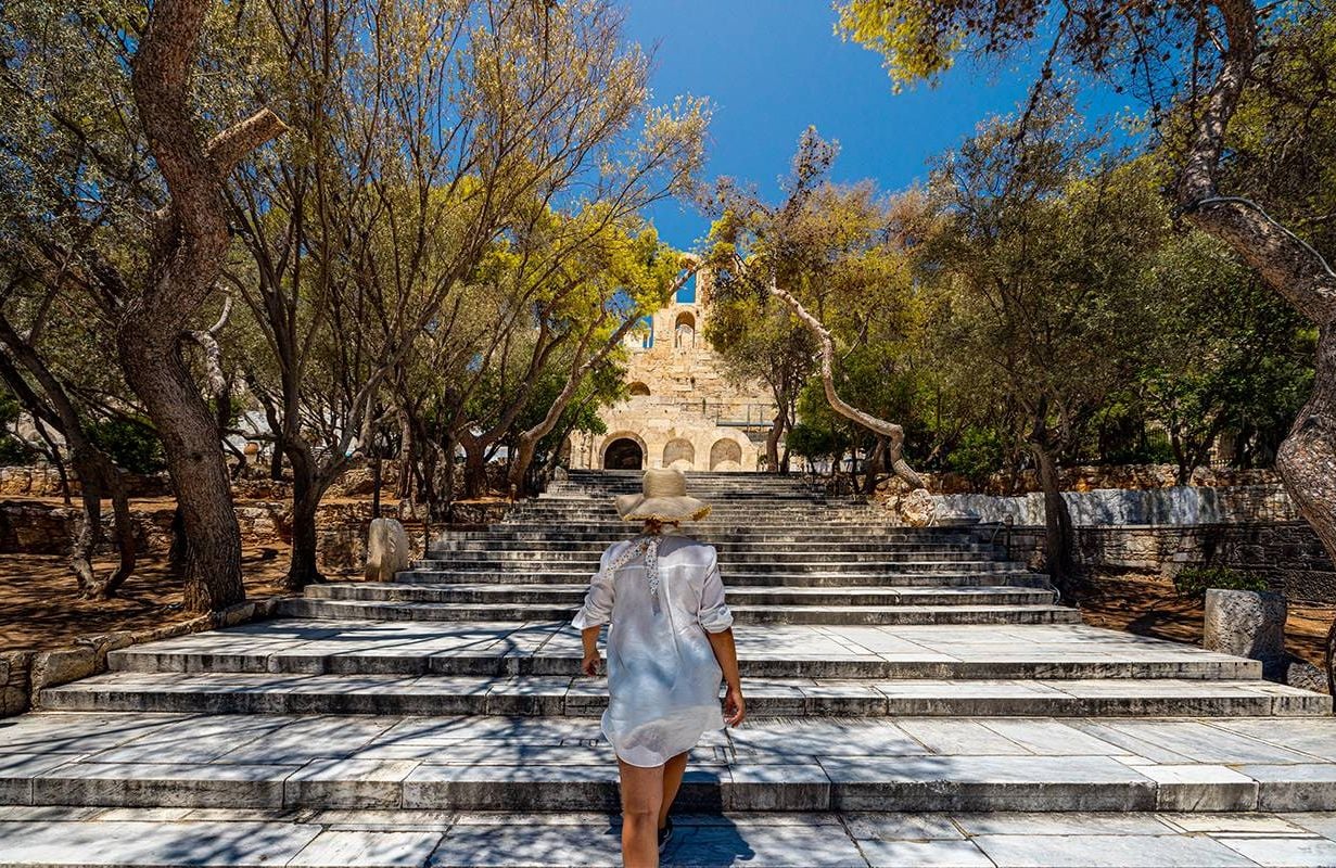 An older solo traveler walking up steps in Greece. Next Avenue