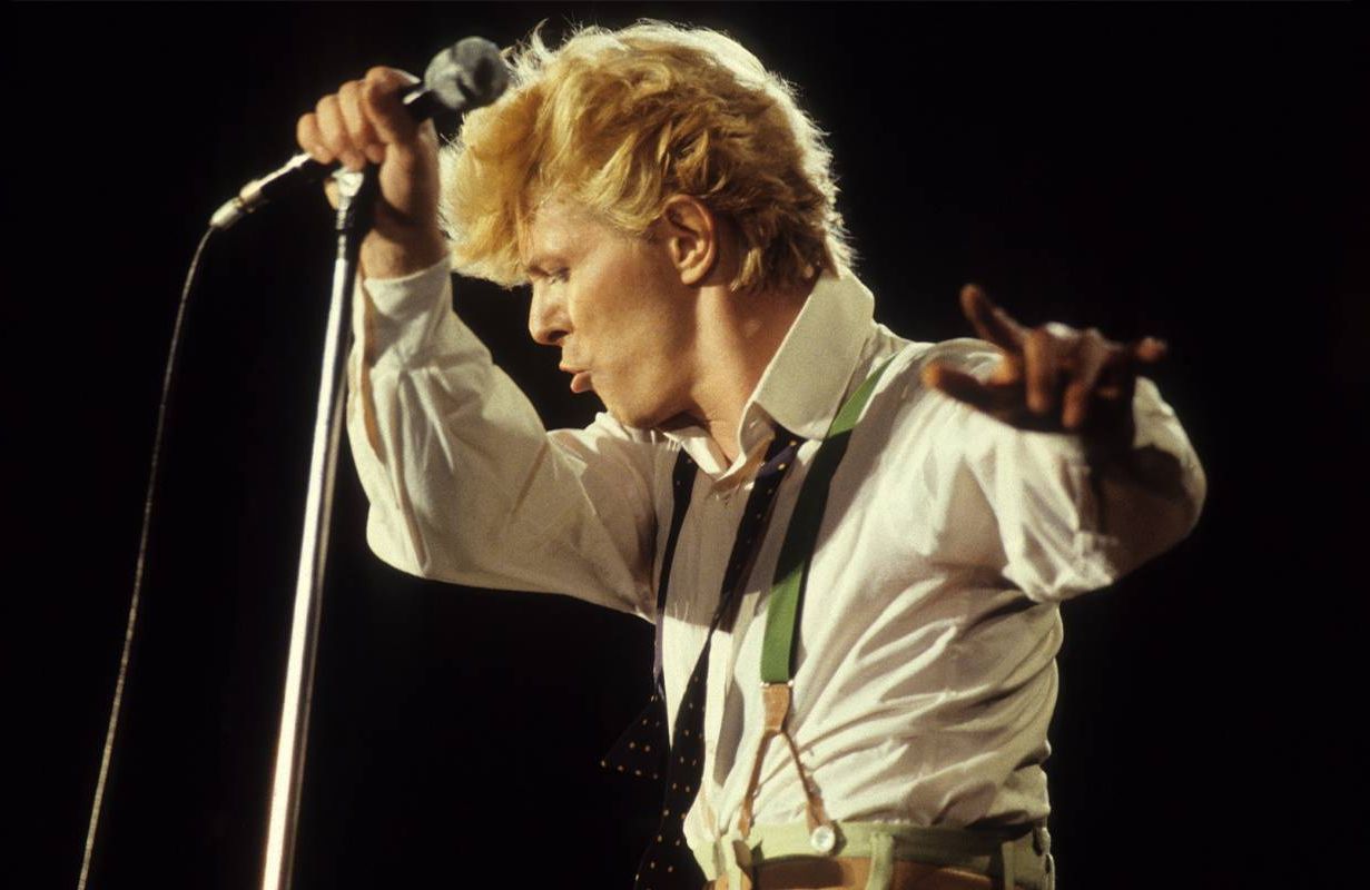 David Bowie holding a microphone and dancing while on stage. Next Avenue