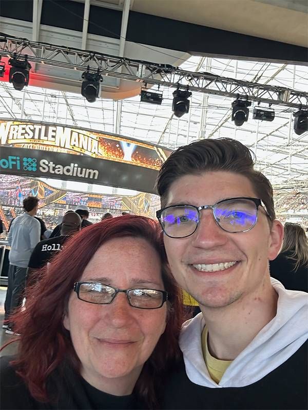 A mother and son taking a selfie in front of a "wrestlemania" sign. Next Avenue