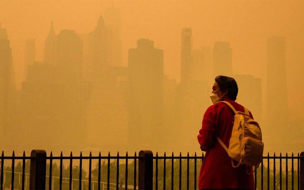 A person standing outside wearing a mask with wildfire smoke in the air. Next Avenue