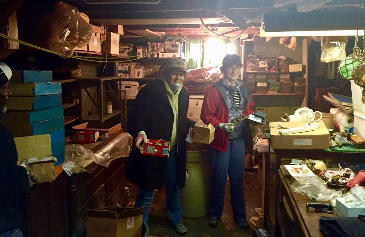 Two women standing in a cluttered basement.