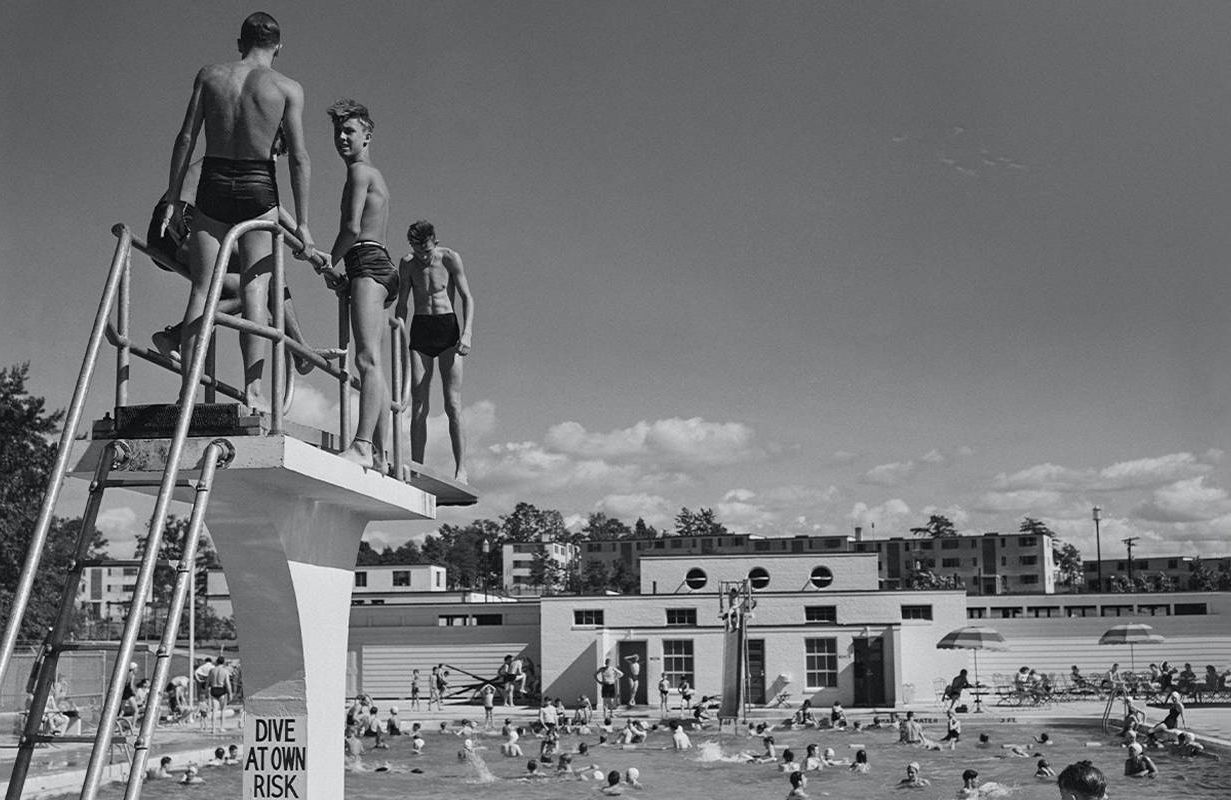 A vintage photo of young people swimming at a public pool. Next Avenue