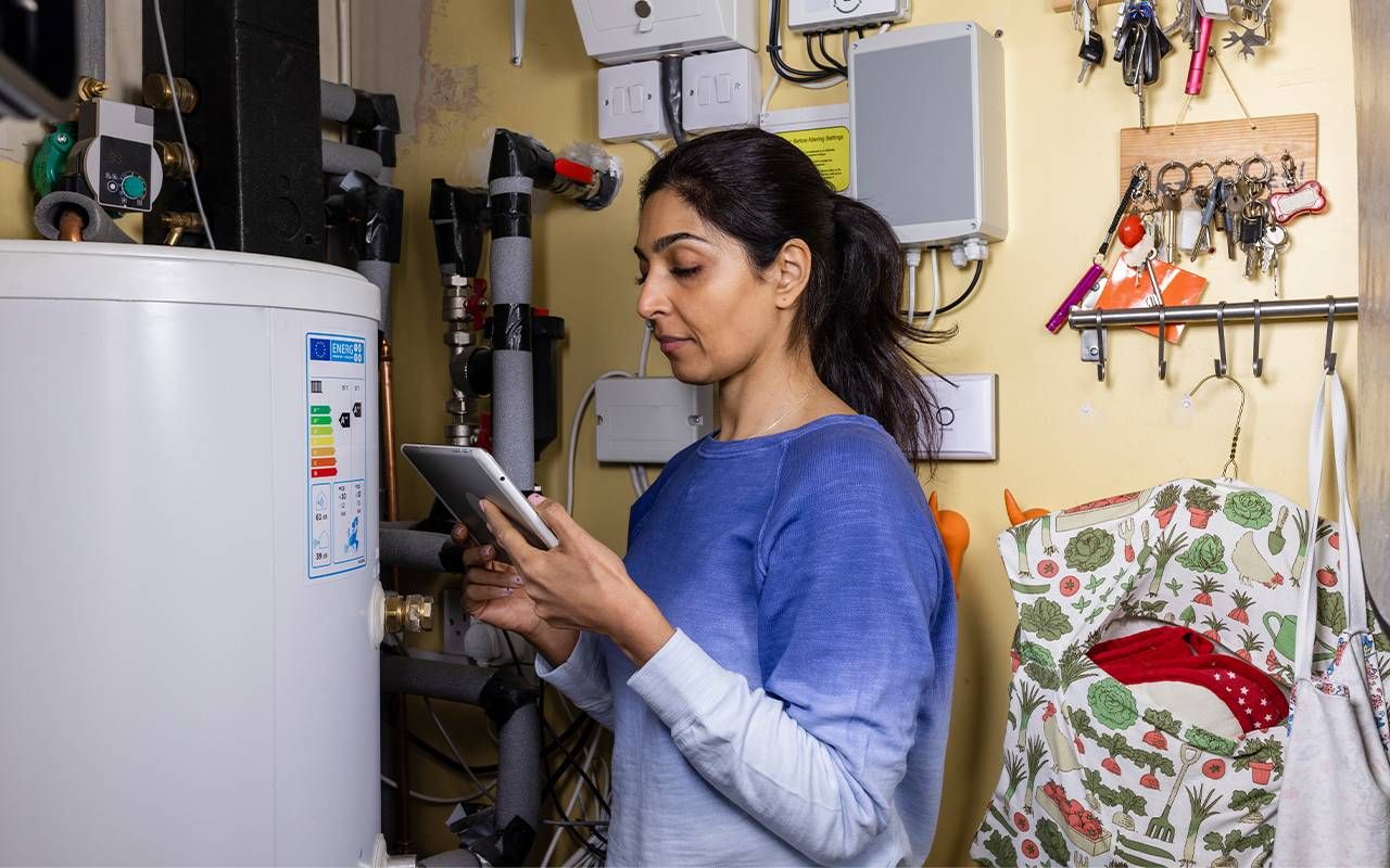 A person adjusting their home thermostat. Next Avenue