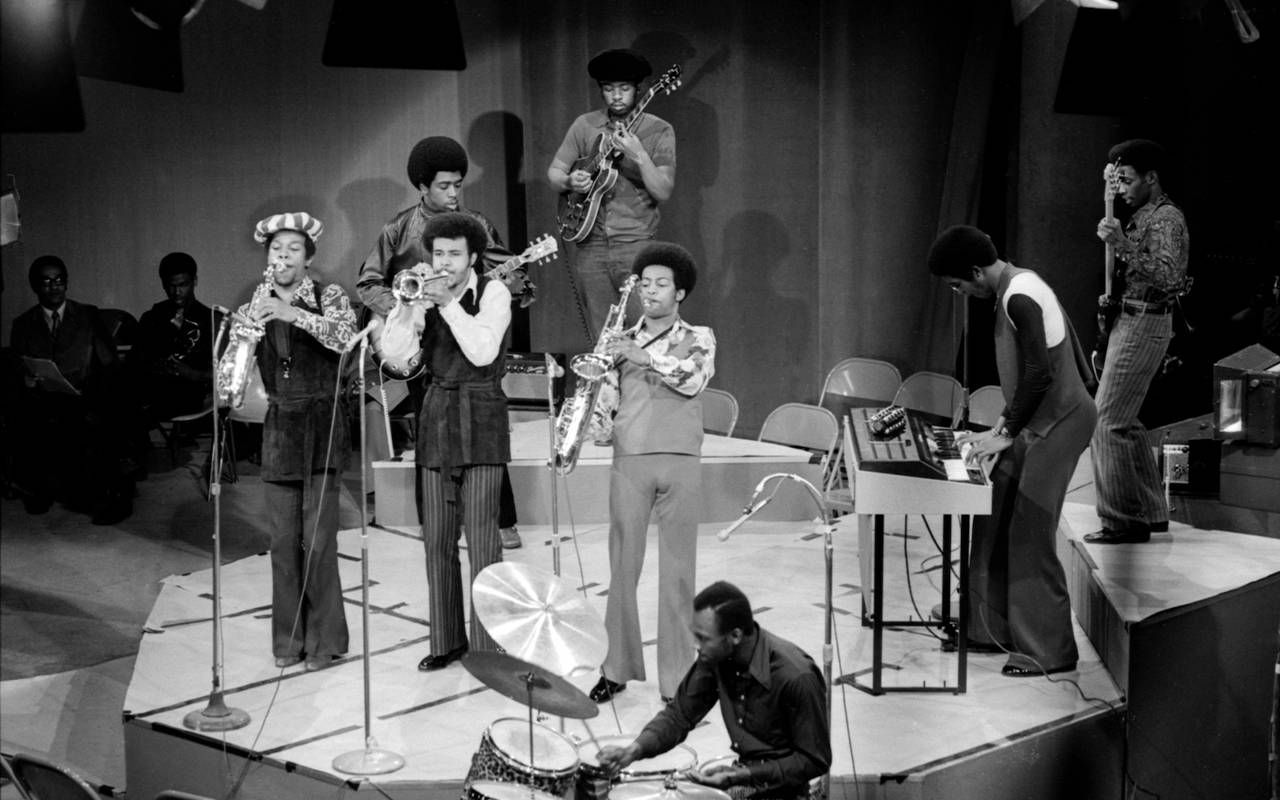 A black and white photo of a band playing on stage. Next Avenue