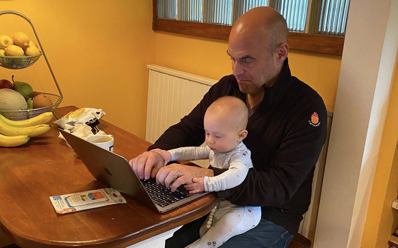 A man working on his laptop with a baby on his lap. Next Avenue