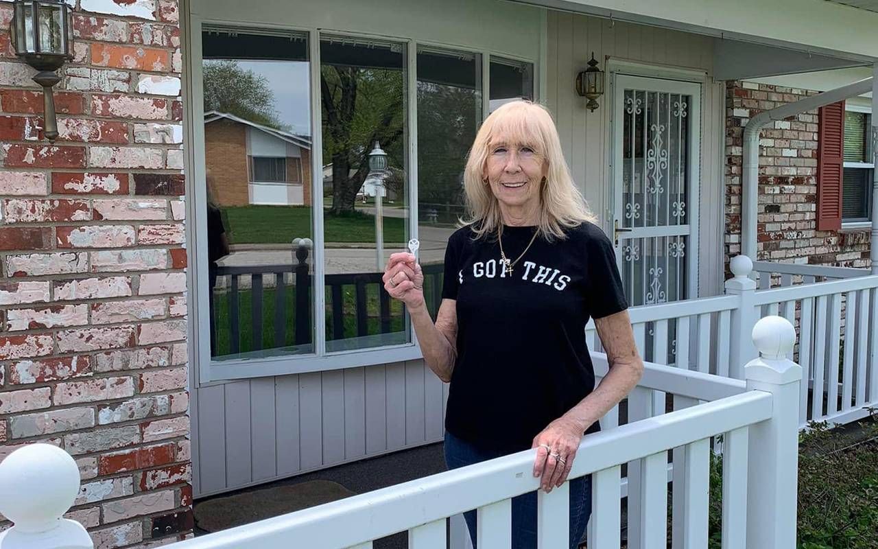 A woman standing outside in front of a house. Next Avenue