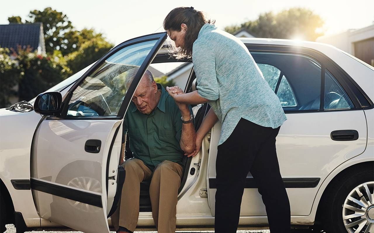 An adult daughter helping her older father out of the car. Next Avenue