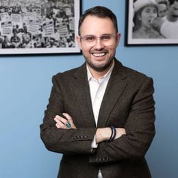 A man smiling and wearing a suit