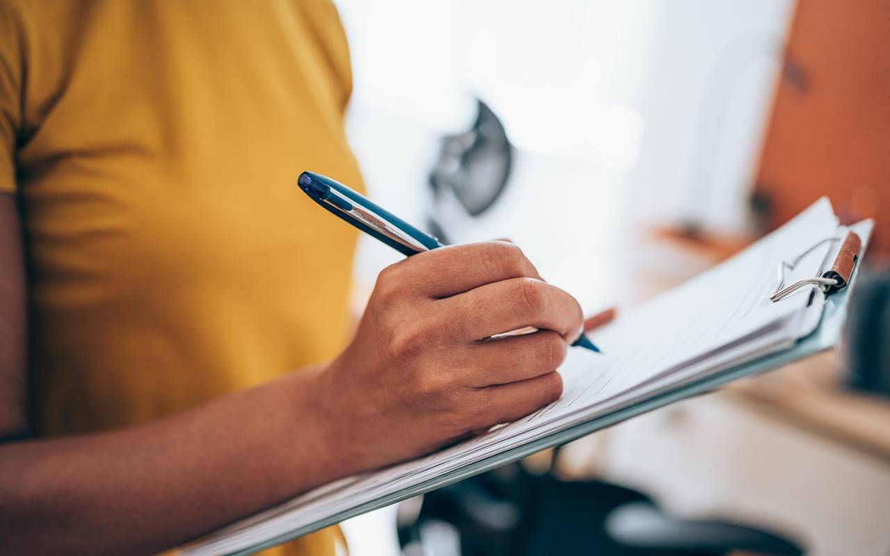 A close up of a woman writing noted down at work. Next Avenue