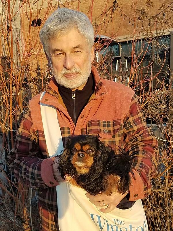 A man smiling with a newspaper bag and a small dog. Next Avenue, local journalism