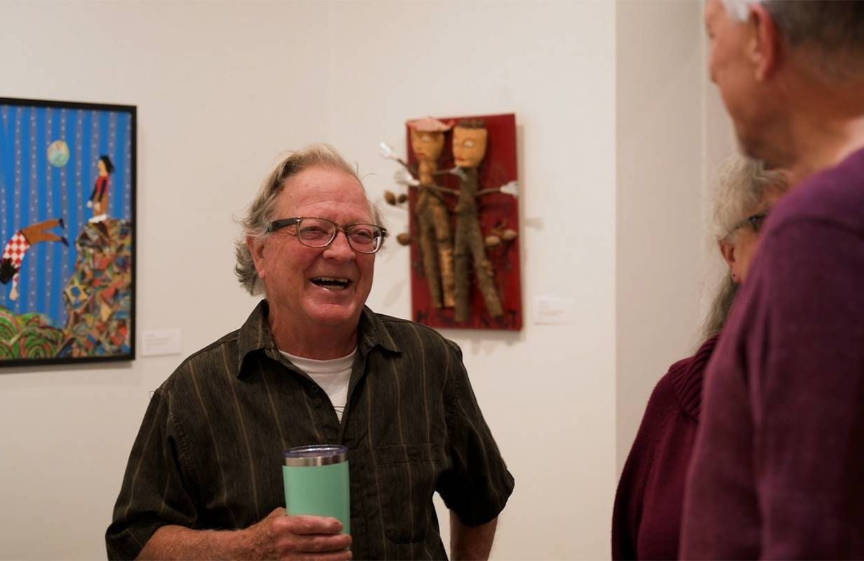 A man smiling and laughing in an art gallery. Next Avenue