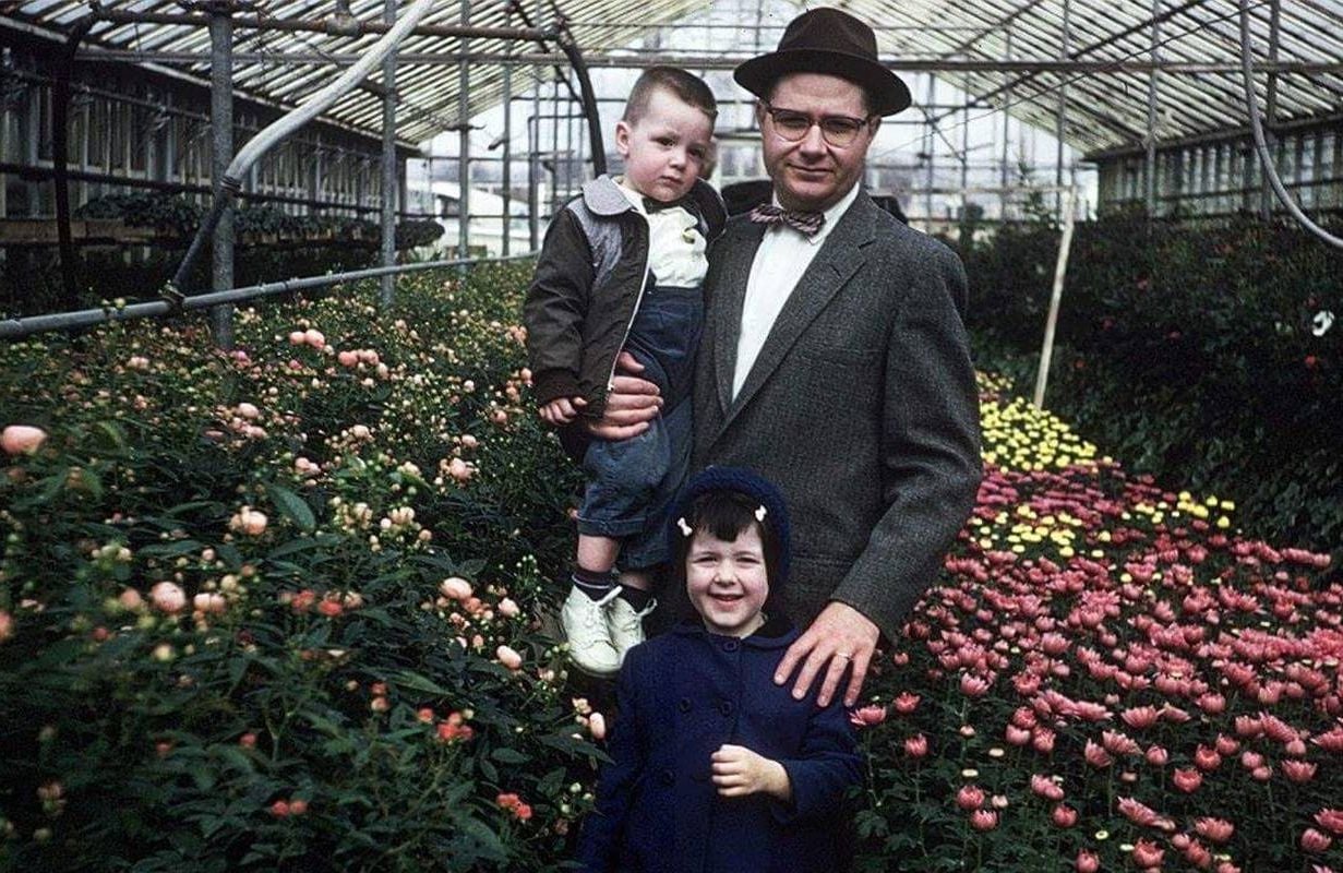 An old photo of three people smiling inside a greenhouse. Next Avenue