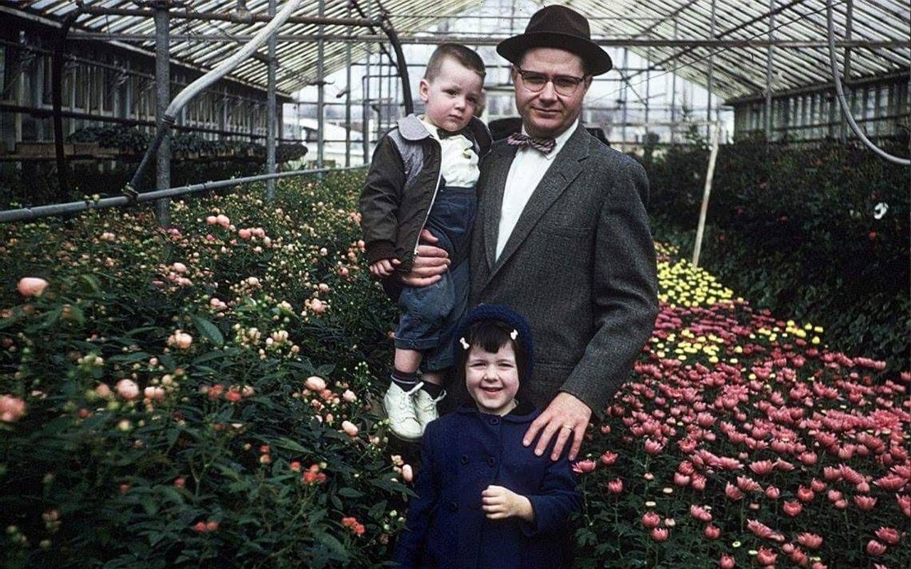 An old photo of three people smiling inside a greenhouse. Next Avenue